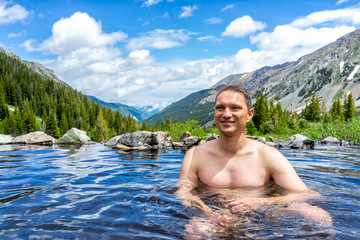 Happy man swimming in hot springs water on Conundrum Creek Trail in Aspen, Colorado in 2019 summer