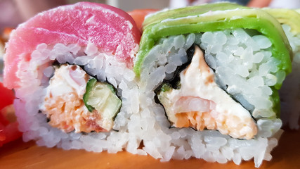 Rainbow sushi roll with salmon, eel, tuna, avocado, king prawns. Beautiful serve in the restaurant. Sushi menu. Japanese food