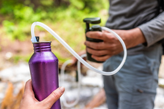 Man and woman couple using water filter on hiking trail river in Colorado to purify drinking water into bottle