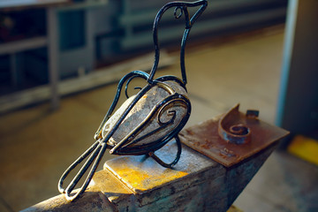 Bird made of iron and stone. The product, handmade by a blacksmith.