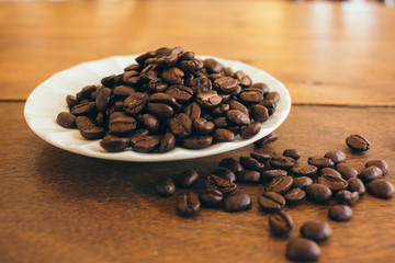 Coffee beans in a white plate on a wooden table