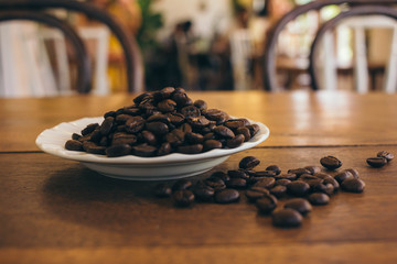 Coffee beans in a white plate on a wooden table