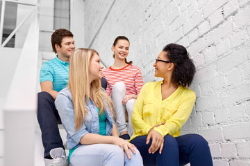 friendship and people concept - smiling teenage friends or students hanging out on stairs