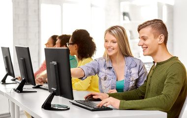 education, technology and learning concept - group of happy international high school students or classmates in computer class