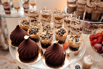 Wedding candy bar. Catering of wedding day. Candy bar. Wedding reception table with sweets, candies, dessert, meringues, fruit tart, cupcakes, muffins, cakes, eclairs