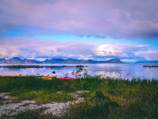 Photo of norway with sea, cloudy sky, colorful boats on summer evening