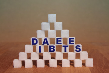 the word DIABETES is written on a high sugar pyramid built of sugar cubes, concept of excess sugar...
