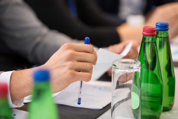 business and people concept - hands of businessman with pen and papers at conference