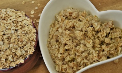 boiled oatmeal and raw cereal on a wooden background