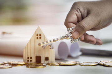 Ownership hold key against house with miniature home for protect and insurance document with white...