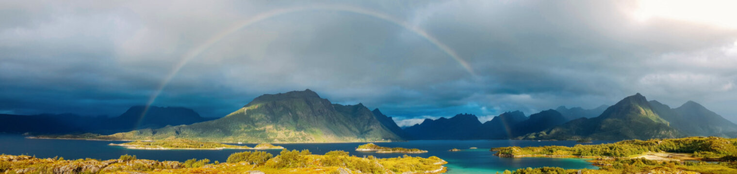 Panoramic photo of rainbow, sea, hills, blue sky in Norway on summer.