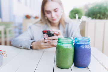 Young blondie woman with smartphone in hands in outdoor cafe  
