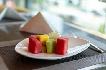Fruit salad, sliced watermelon, melon and pineapple in squares. Sliced fruits on a plate.