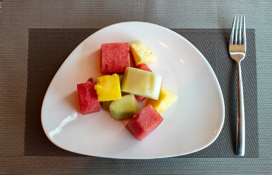 Fruit salad, sliced watermelon, melon and pineapple in squares. Sliced fruits on a plate, top view.