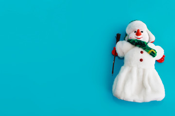 Christmas decorative toy snowman in a white fur coat and hat on a blue background for the New Year holiday