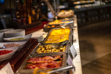 Buffet breakfast at a Chinese hotel. Focus on sausages on blurry background of food trays. Breakfast is included in the hotel.