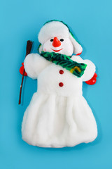 Christmas decorative toy snowman in a white fur coat and hat on blue background for the New Year holiday