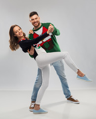 christmas, people and holidays concept - happy couple dancing at ugly sweater party