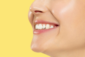 Close up shot of young woman on yellow studio background. Beautiful female model with well-kept skin. Concept of human emotions, facial expression, beauty, healthy lifestyle. Lips, teeth smiling.