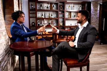 Two businessmen cheering with glasses of wine