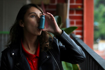 Health and medicine - Young girl using blue asthma inhaler to prevent an asthma attack. - obrazy, fototapety, plakaty
