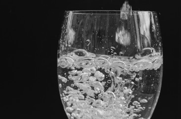Pouring water into glass on black background