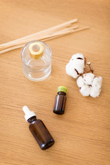 home perfume and aromatherapy concept - aroma reed diffuser, essential oil and branches of cotton flower on wooden table