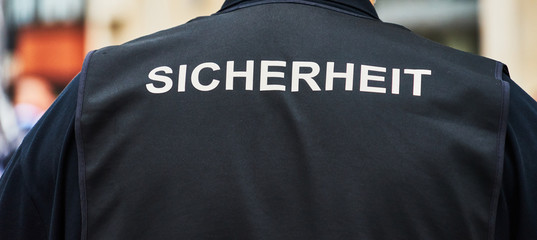Back view of a guard with a black waistcoat with the German inscription 