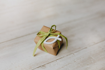 Religion, Glaube - Geschenk mit recyclingpapier, grüner Schleife und weißem Fisch