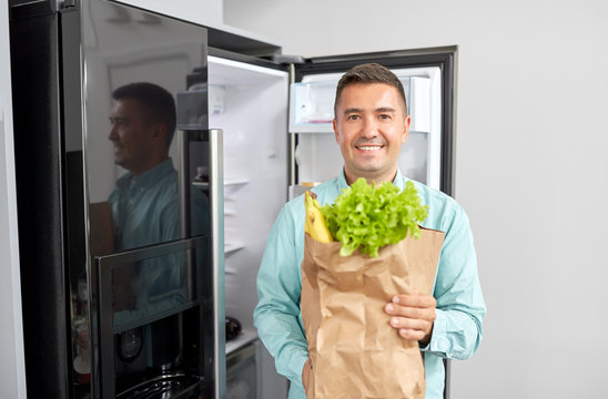 Eating, Diet And Storage Concept - Smiling Middle-aged Man With New Purchased Food In Paper Bag At Home Fridge