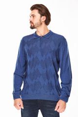 Fototapeta premium man with beard and dark hair stands on a white background in blue sweater with zip and collar and dark jeans, he has a gold watch on his arm and looks on the left direction