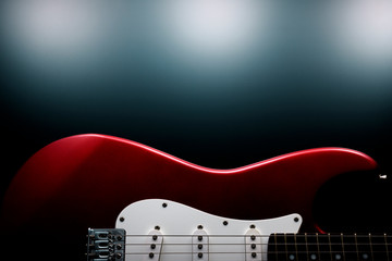 Red electric guitar on dark background.