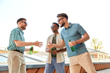 leisure, male friendship and people concept - happy men or friends meeting and drinking beer at rooftop party in summer
