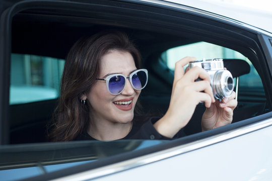 young woman taking photos from car window
