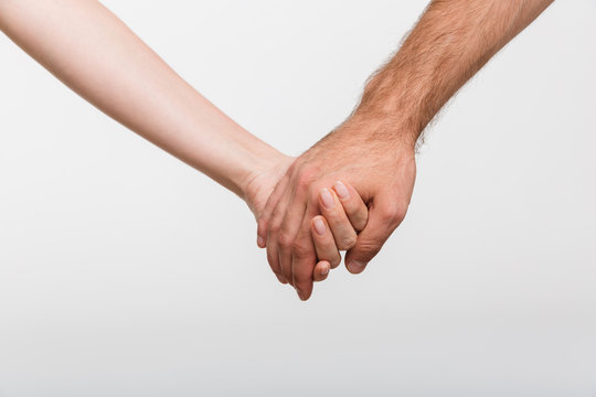 Man and woman holding hands of each other isolated over white wall background.
