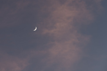 Obraz na płótnie Canvas a new moon in the dusk sky and white clouds