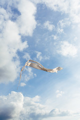 White kite flying against the blue sky full of clouds. Vertical image