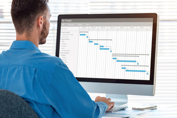 Project manager in office scheduling tasks and progression of milestones completion with Gantt...