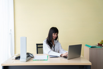 The happy female doctor sat on the working chair while set up blood pressure monitor in the examination room