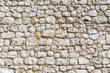 An old time damaged wall made of rough stone. Natural background for design.