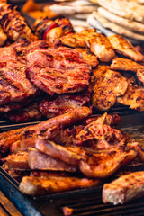 Juicy steaming meat on a charcoal grill, pork steaks, chicken breast, sausages, pieces of meat chops at a street food festival
