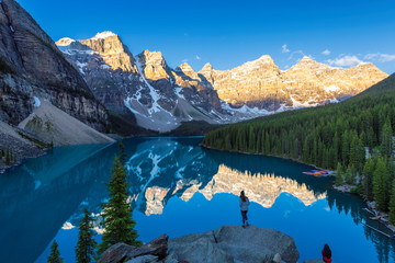 Beautiful sunrise under turquoise waters of the Moraine lake with snow-covered peaks in Banff...