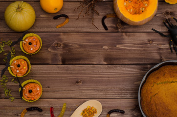 Halloween background with copy space: pumpkin pie and cupcakes with orange pumpkins