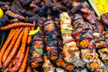 Juicy steaming meat on a charcoal grill, pork steaks, chicken breast, sausages, pieces of meat chops at a street food festival