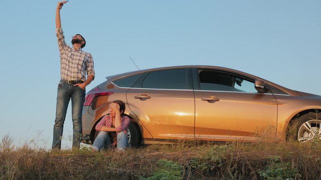 Couple traveling by car catches a phone signal while standing on the side of the road