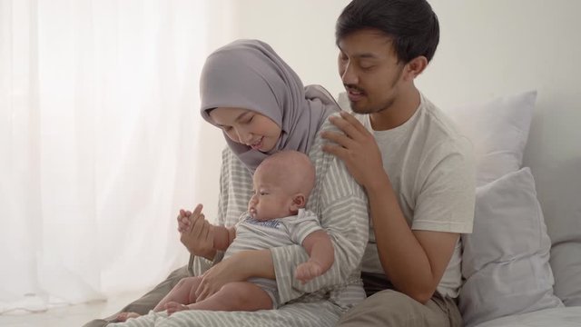 lovely muslim couple with their infant baby boy in bedroom