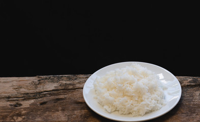 Jasmine rice in white dish and on a old wooden table and black background, Selective focus, Vintage style..