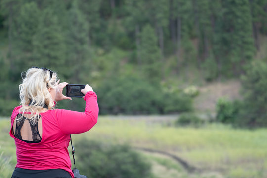 Blonde Woman Photographer Takes Pictures With Her Smart Phone At A Scenic Overlook