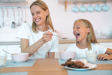 mother feeds her beautiful daughter with chocolate flakes and laughs loudly. have a good time together, dressed alike