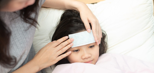 Fototapeta na wymiar Mother attach cooling fever patch gel for reduce temperature her daugther at home.